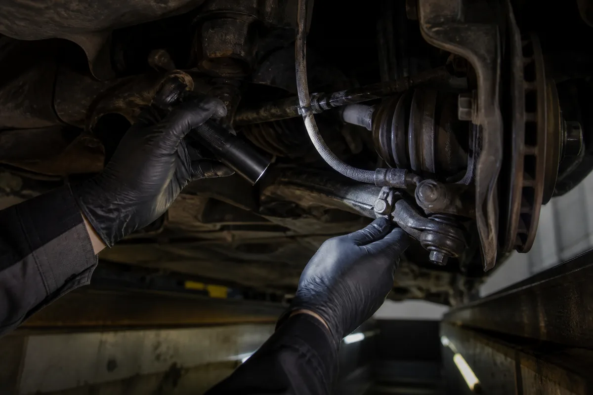 Contrôleur technique inspectant le train avant d&rsquo;une voiture sur une fosse d&rsquo;atelier